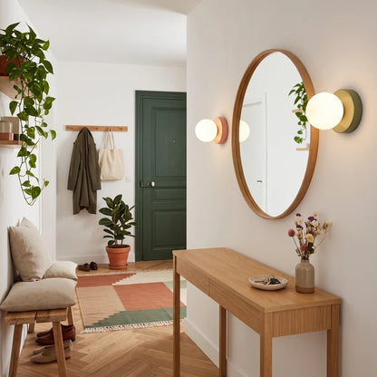 Appliques murales Macaron rose et vert sauge autour d’un miroir dans une entrée