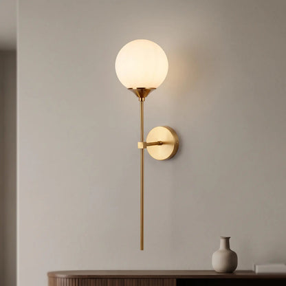 Applique murale fine en laiton doré avec diffuseur boule en verre blanc opalin sur mur gris clair