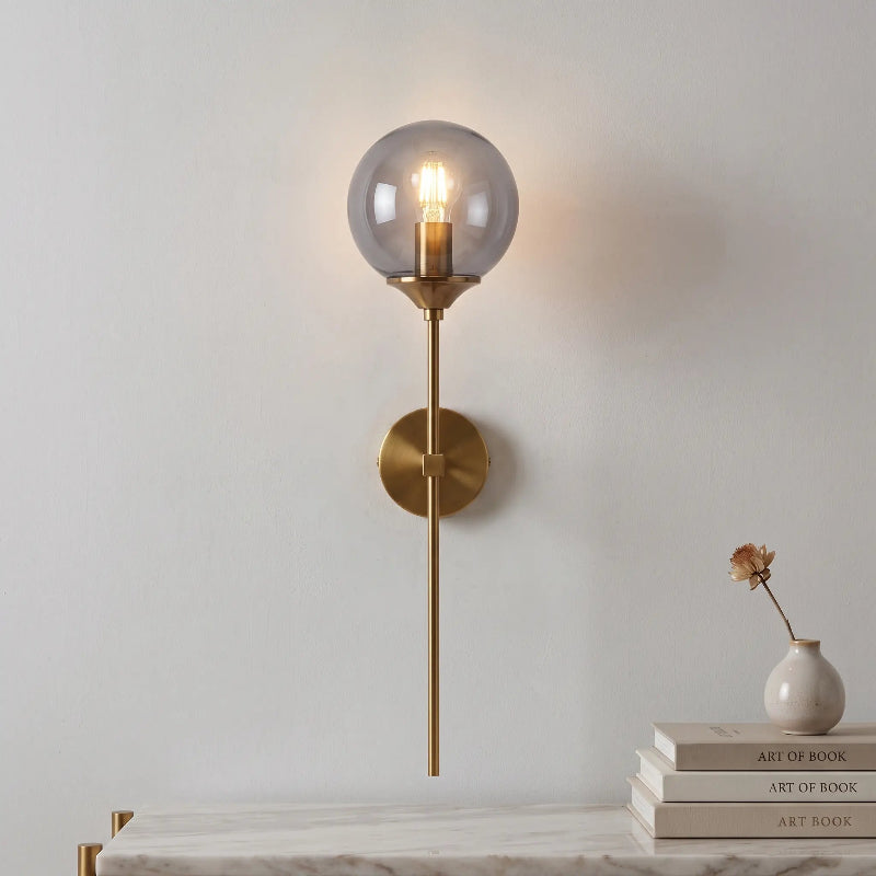 Applique murale design à tige longue en métal doré et globe en verre teinté au-dessus d'une étagère