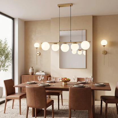 Deux appliques murales dorées encadrant un tableau dans une salle à manger moderne avec table en bois et suspension