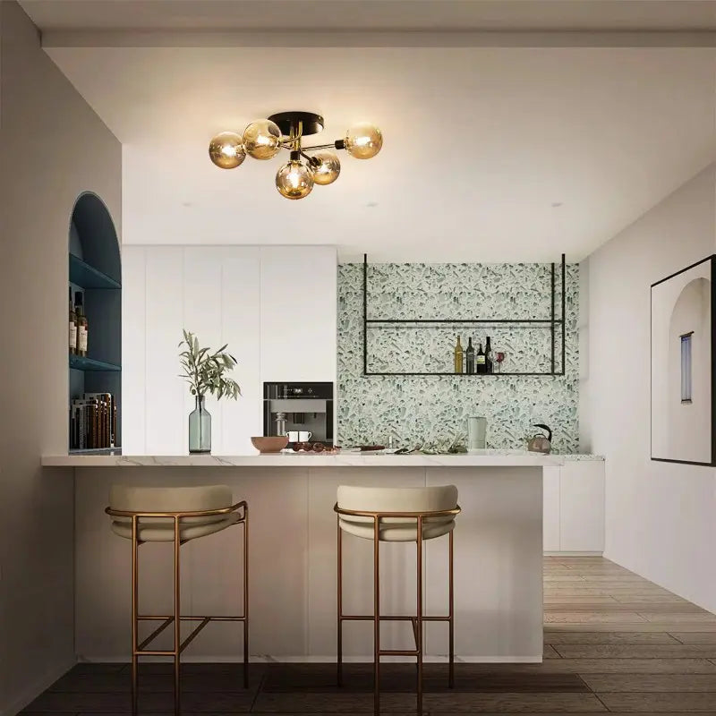 Plafonnier à branches dorées installé au plafond d'une cuisine moderne ouverte avec îlot et tabourets