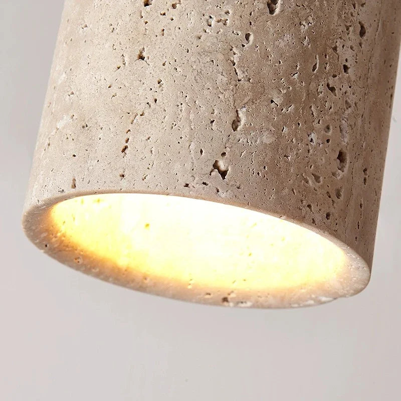 Gros plan sur la texture poreuse de la pierre de travertin beige et le faisceau lumineux chaleureux du spot