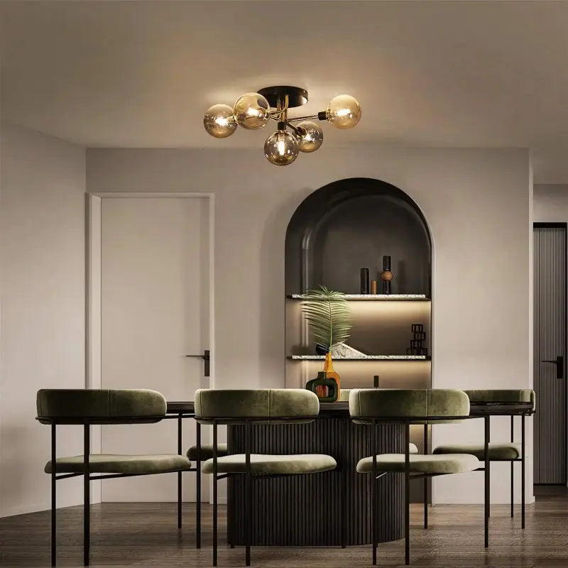 Plafonnier design au-dessus d'une table à manger ronde entourée de chaises en velours vert