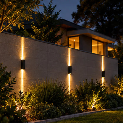 Trois appliques LED noires sur un mur de jardin moderne