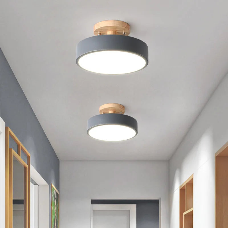Plafonniers LED ronds gris et bois naturel alignés au plafond d'un couloir moderne