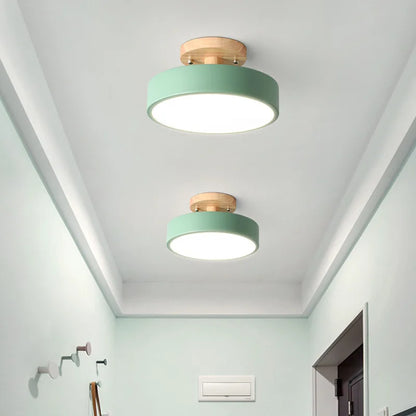 Plafonnier LED rond scandinave vert pastel et bois naturel installé dans un couloir moderne